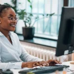 Black woman working at a desktop computer in an office
