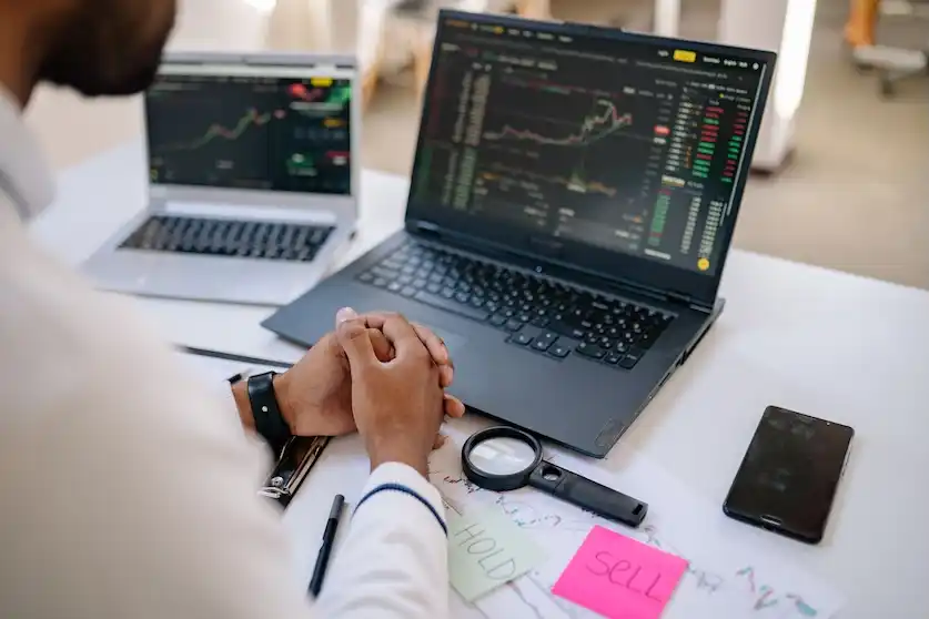 Caption: Business professional analyzing stock market data on dual laptops in an office Source: Yan KruKox via Pexels https://www.pexels.com/photo/person-sitting-in-front-of-a-laptop-7691769/