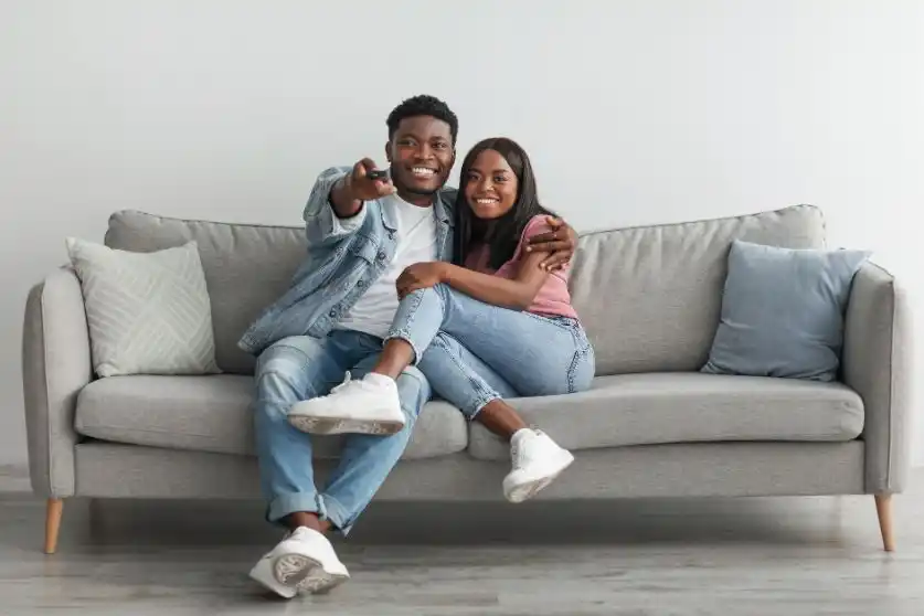 Black couple watching TV on a grey couch
