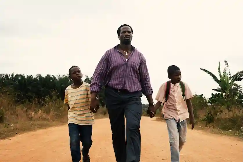 Still from the film, My Fathers Shadow. Folarin walking hand in hand with his two sons.