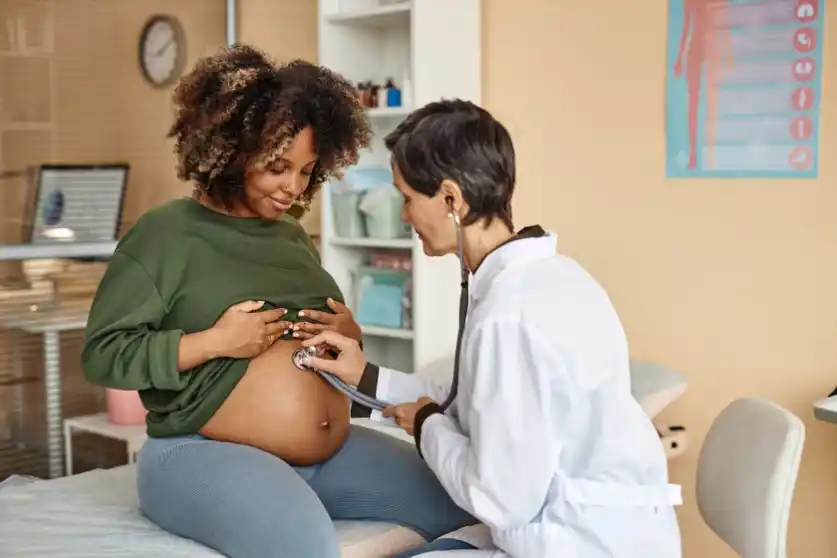 Pregnant Black woman at a prenatal appointment with a white doctor