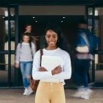 Black student holding a laptop at a university